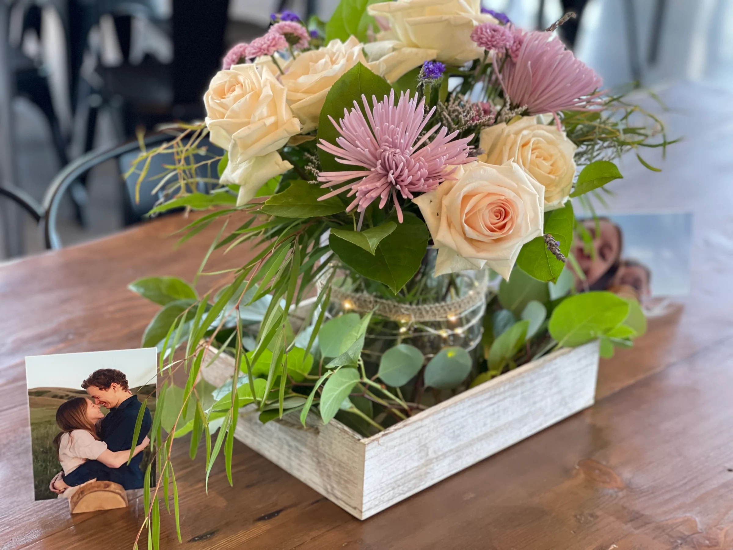 Cream and pink flowers in a glass jar on a wooden tray